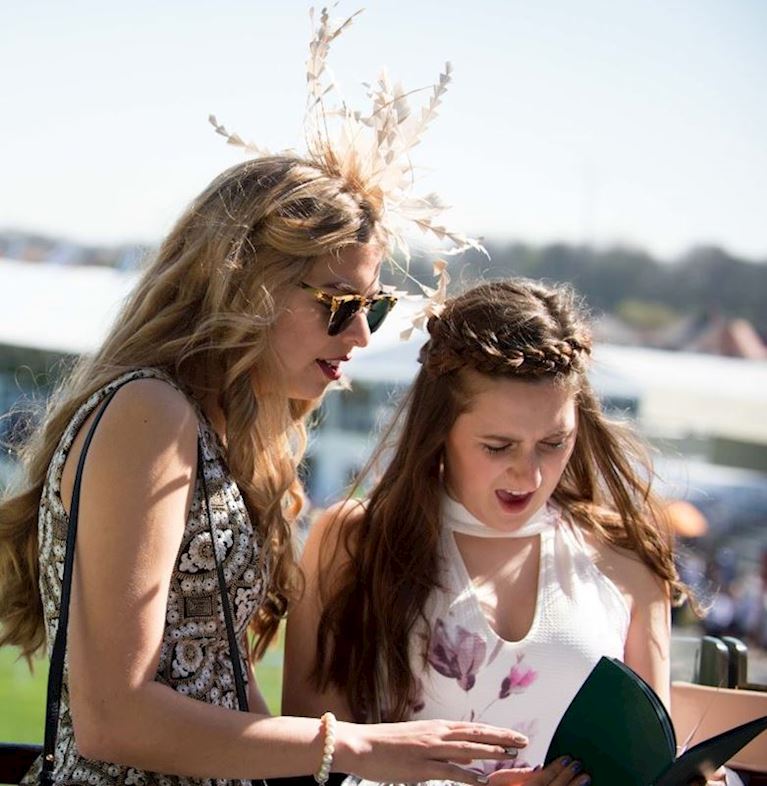 two women reading the grand natioanl racecard in the sun